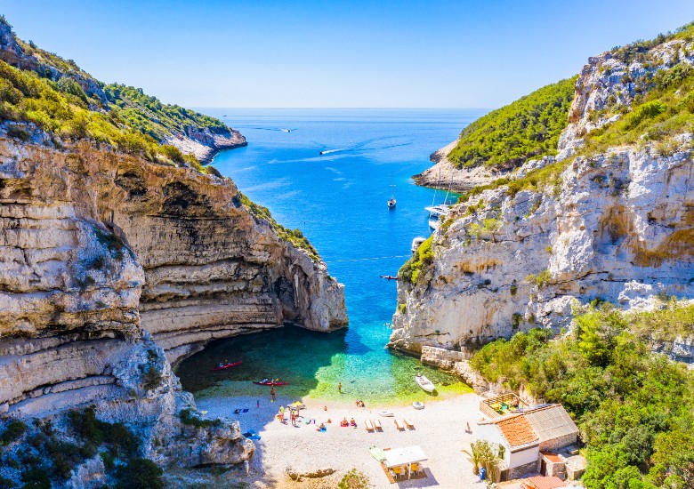 View of Stiniva Cove with pebble beach, turquoise water and steep cliffs